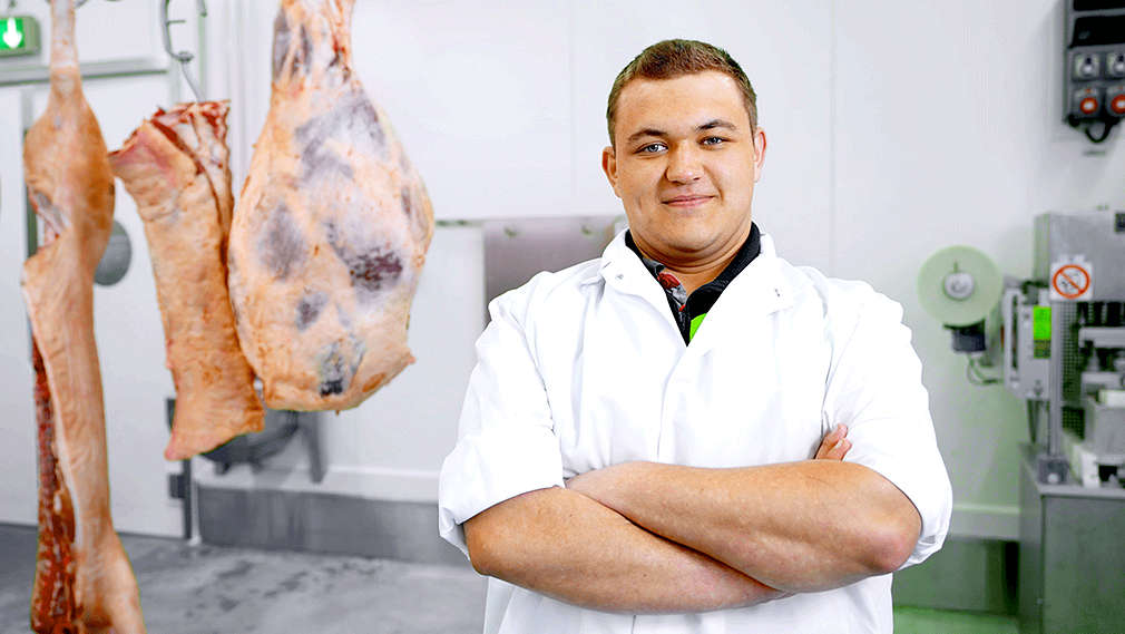 Mitarbeiter der Fleischwerke steht vor Fleisch