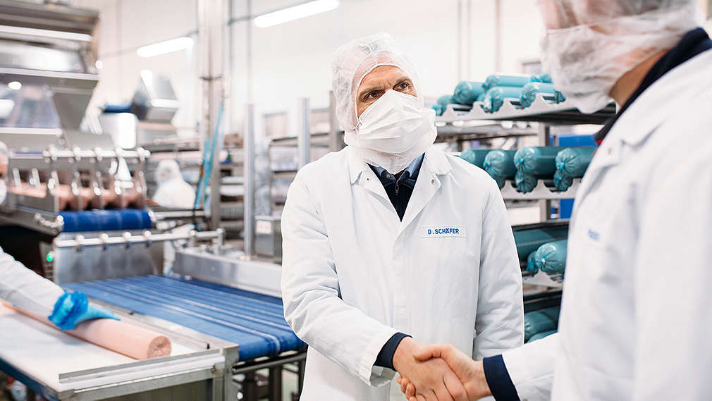 Mitarbeiterin der Fleischwerke zeigt auf Monitor mit Messwerten