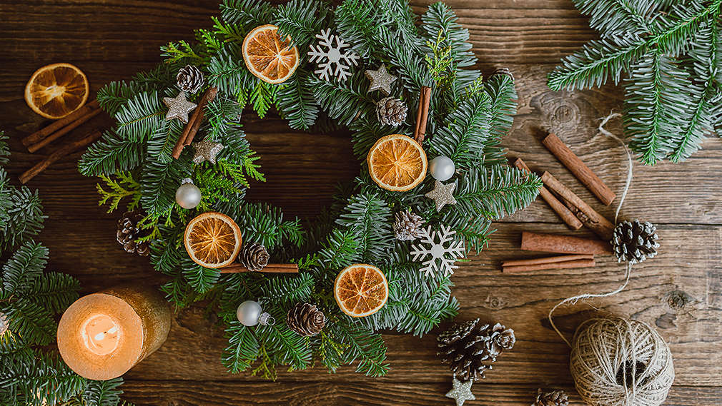Selbst gemachter Adventskranz aus Tannenzweigen dekoriert mit Orangenscheiben, Zimtstangen und Schneeflocken