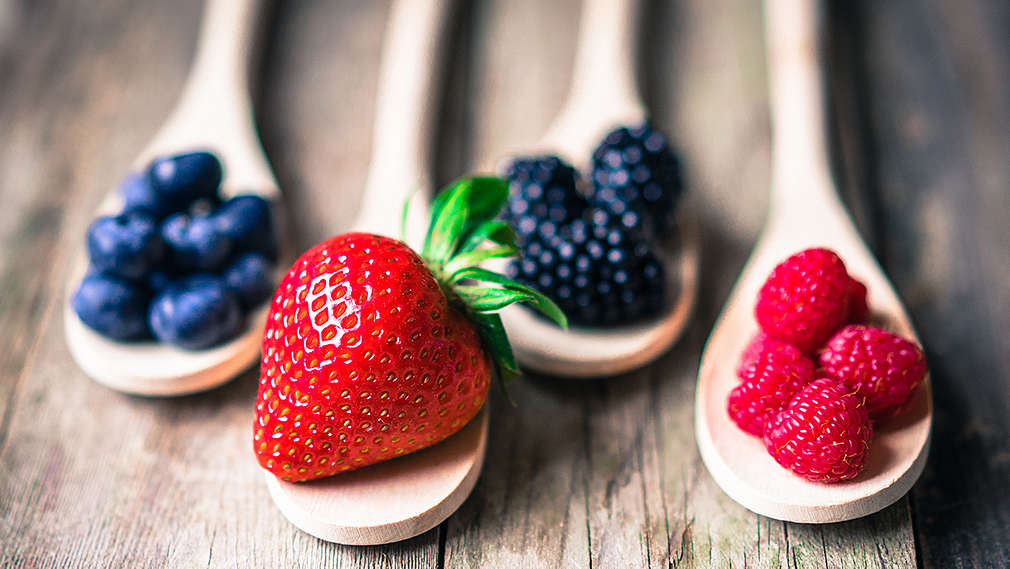Verschiedene Beerensorten auf vier Holzlöffel verteilt