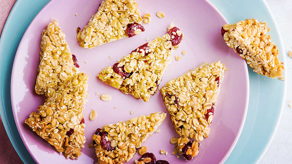 Von oben fotografierte Müsliecken auf einem kleinen rosafarbenen Teller. Darunter steht ein größerer, hellblauer Teller, auf dem weitere zwei Müsliecken liegen