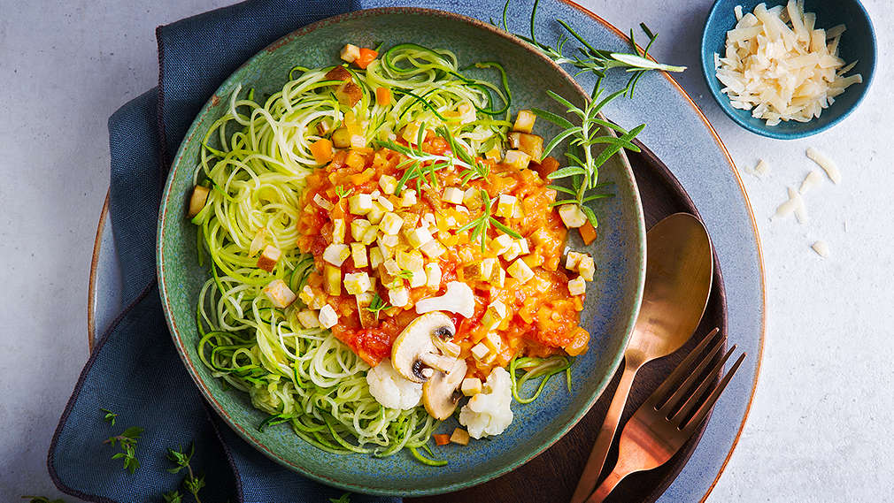 Ein von oben fotografierter Teller mit Zoodles und verschiedenen Gemüsesorten sowie Tofu