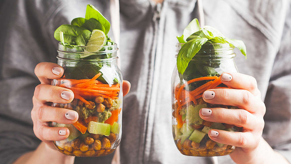 Person hält verschiedene vorbereitete Gläser gefüllt mit Gemüse 