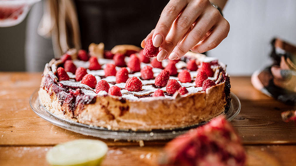 Veganer Kuchen ohne Milchprodukte dekoriert mit Puderzucker und Himbeeren