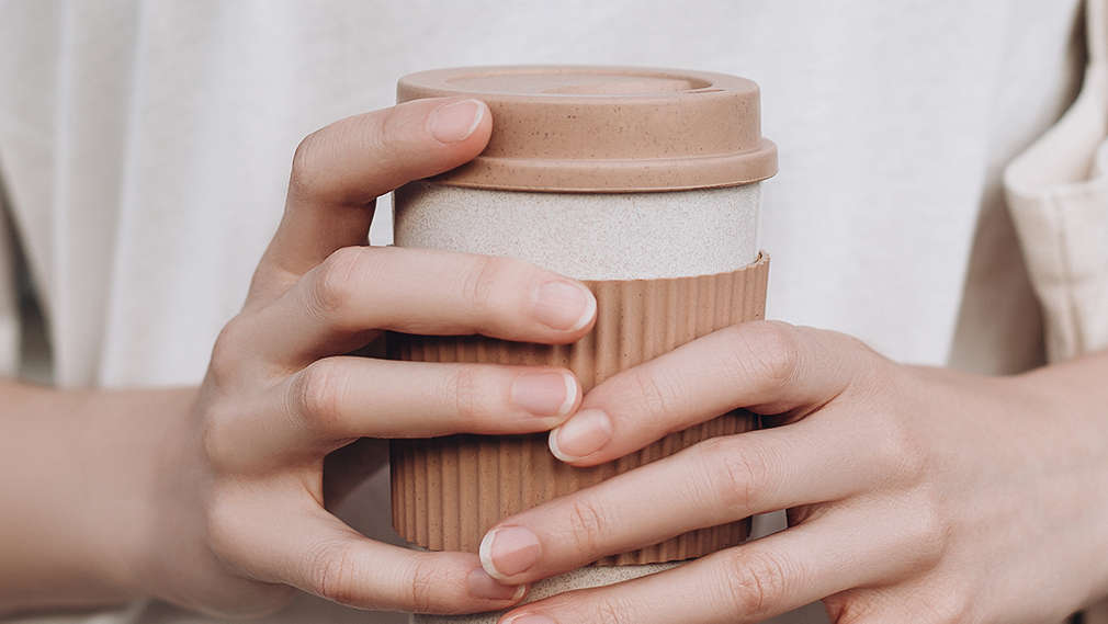 Frau hält Mehrweg-Kaffeebecher