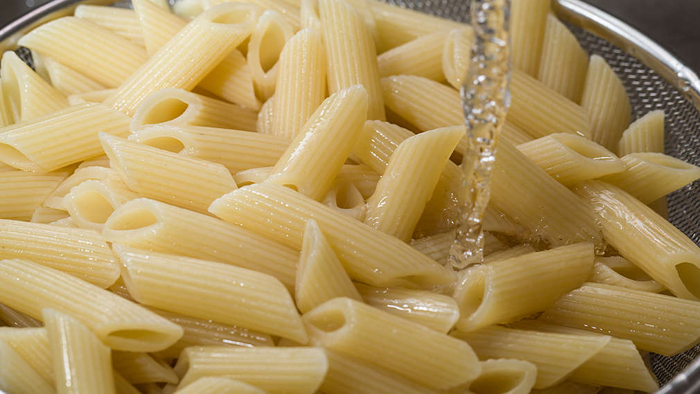 Nudeln werden im Sieb mit kaltem Wasser abgeschreckt