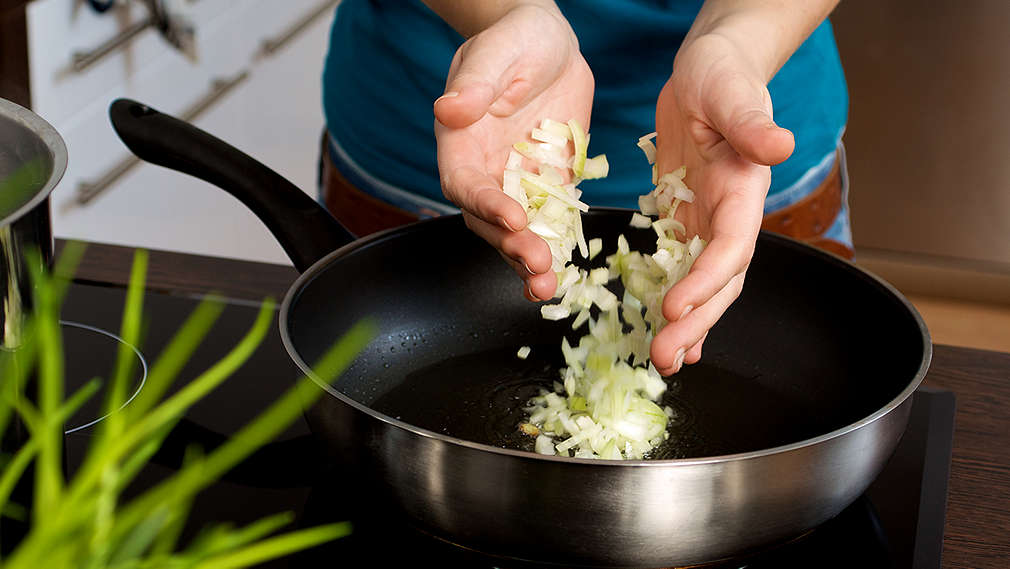 Fein gehackte Zwiebeln werden in eine Pfanne zum Anschiwtzen gegeben