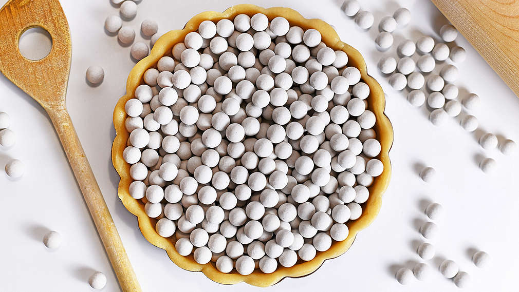 Eine mit Teig ausgekledete Tarteform ist mit Backerbsen zum Blindbacken gefüllt