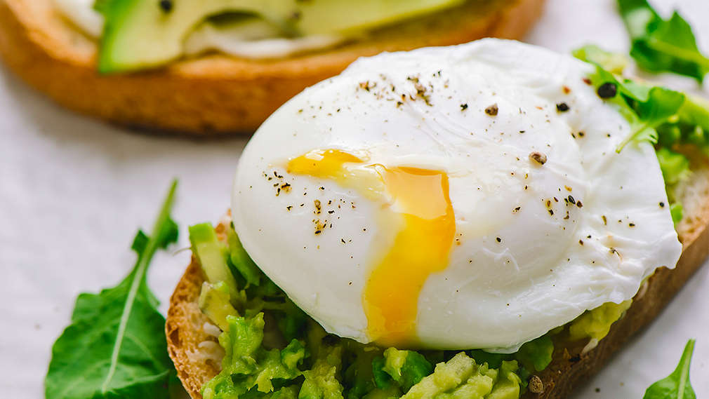 Ein Stück Brot belegt mit Salat und pochiertem Ei