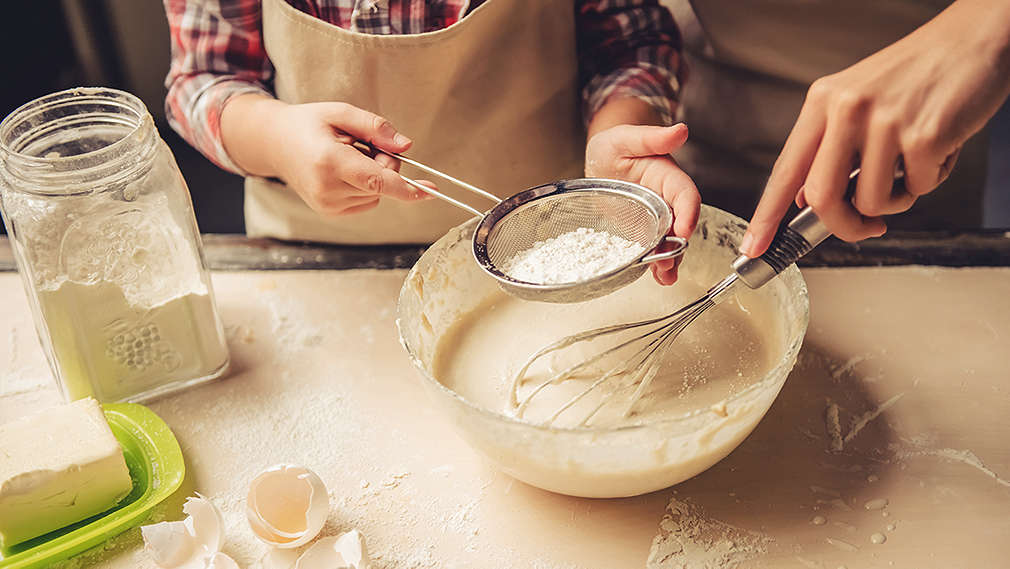 Zwei Personen vermengen Mehl mit einer Teigmasse