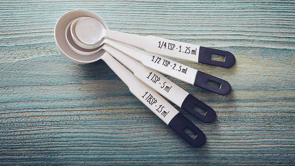 Mehrere Messlöffel liegen auf einem Holztisch