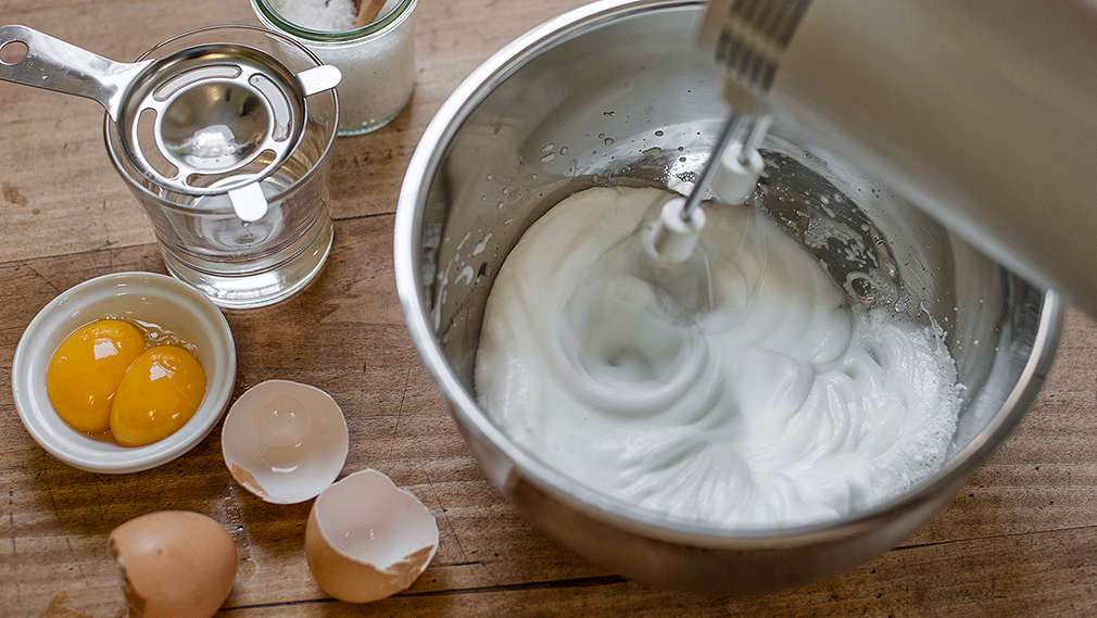 Eischnee wird mit einem Mixer in einem Topf geschlagen