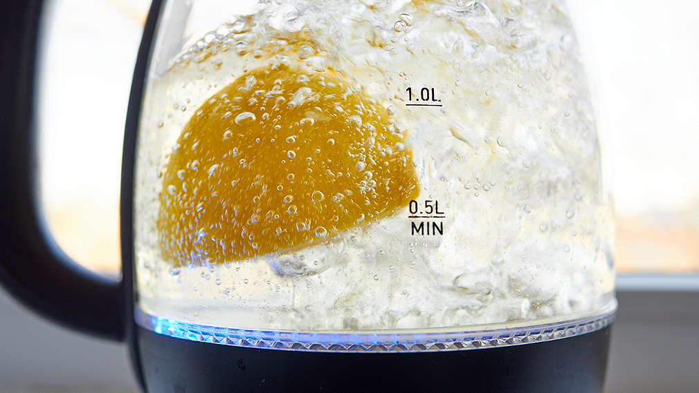 Wasserkocher wird mit einem Stück Zitrone entkalkt