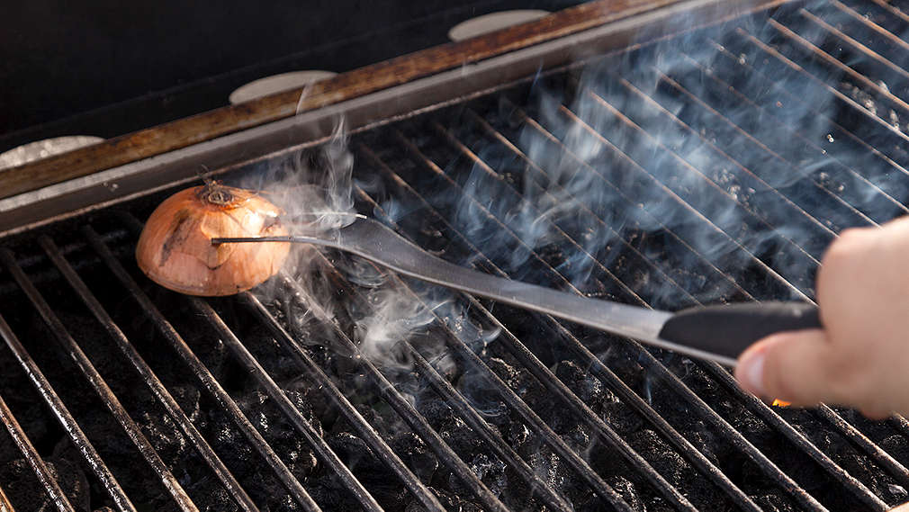 Grillrost wird nach dem Grillen mit einer Zwiebel gereinigt