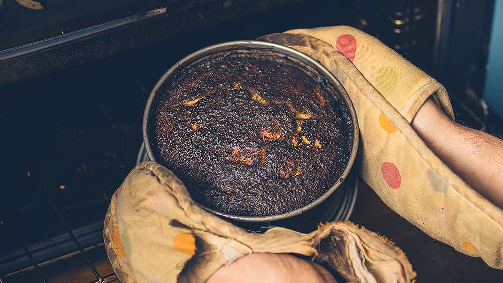 Verbrannter Kuchen wird aus dem Backofen herausgeholt