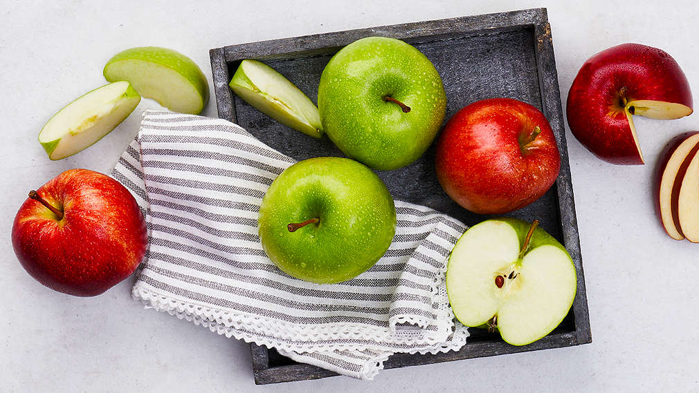 Rote und grüne Äpfel liegen auf einem Tablett