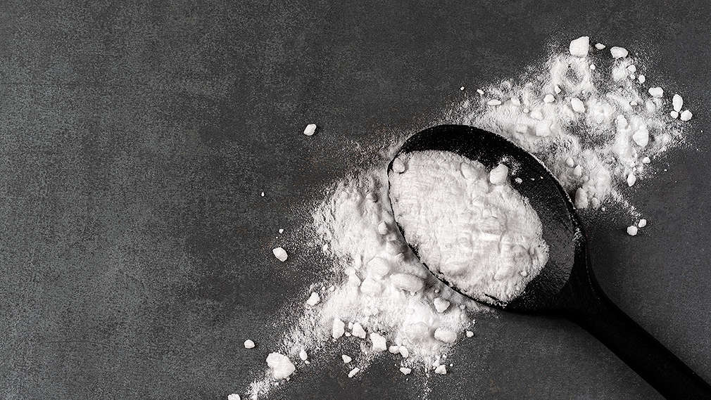 Backsoda auf einem Teelöffel auf dunkelgrauem Hintergrund 