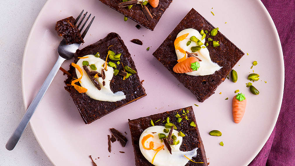Vier Brownies mit Topping und einer Gabel auf einem rosafarbenen Teller