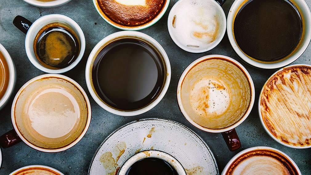 Mehrere Tassen unterschiedlicher Kaffeespezialitäten stehen nebeneinander auf einem Tisch