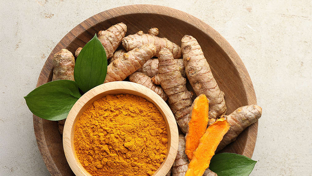 Mehrere geschnittene Kurkuma-Stücke in einer kleinen Schale in den Händen einer Person