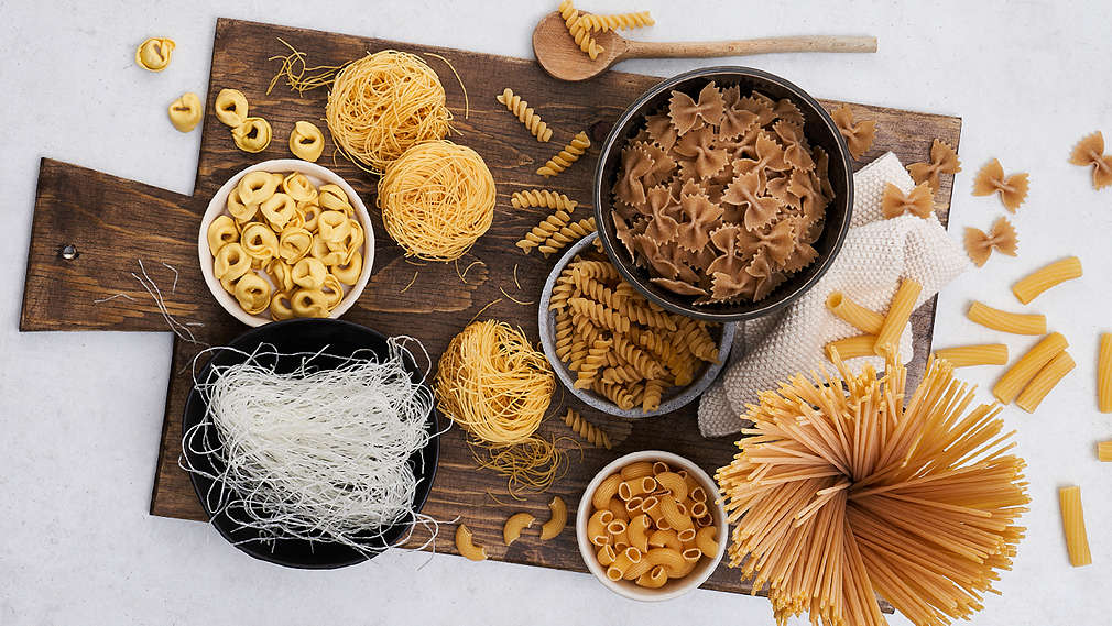 Unterschiedliche Nudelsorten in kleinen Schälchen auf einem Holzbrett