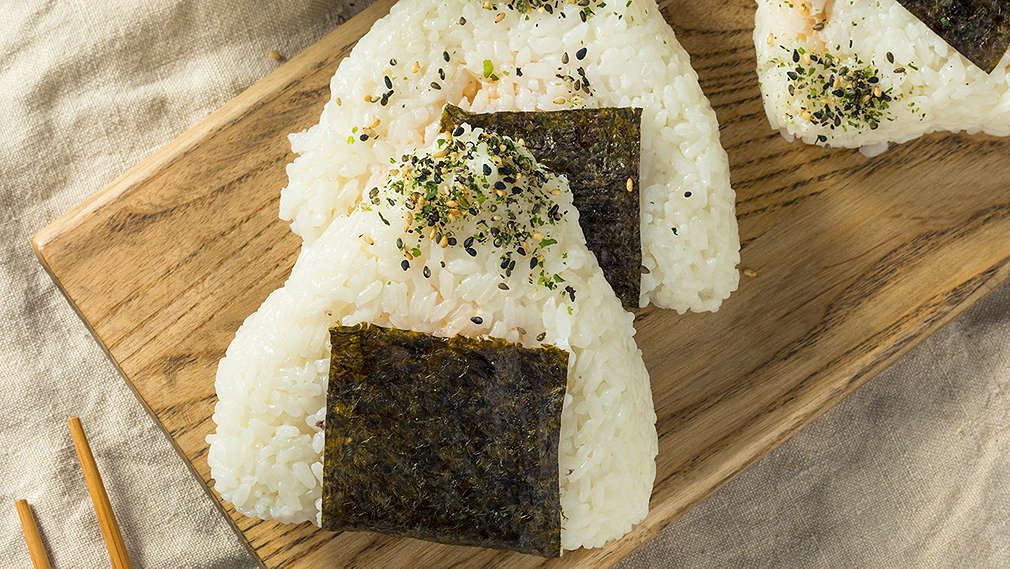 Zu sehen sind japanische Reisbällchen, sogenannte Onigiri, auf einem Holzbrett