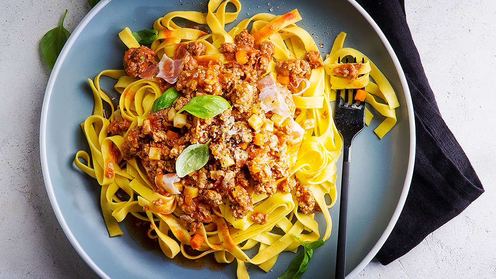 Auf hellem Untergrund liegt eine schwarze Serviette, darauf befindet sich ein Teller mit Bolognese
