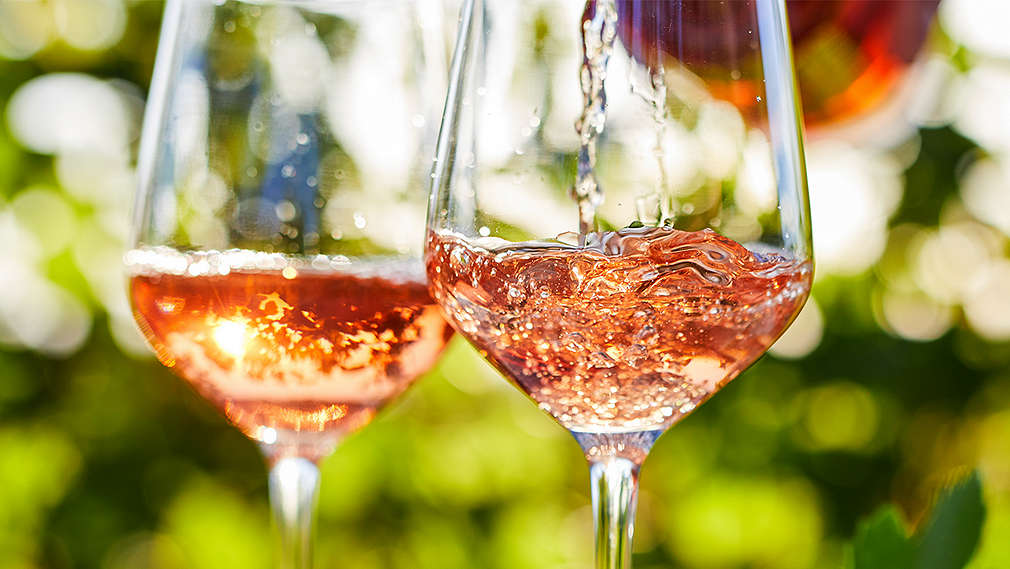 Zwei Gläser mit Roséwein, Hintergrund mit Gartenatmosphäre