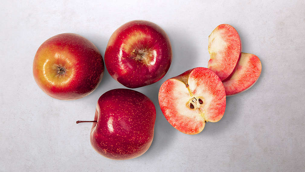 Abbildung von mehreren rotfleischigen Äpfeln, teilweise aufgeschnitten