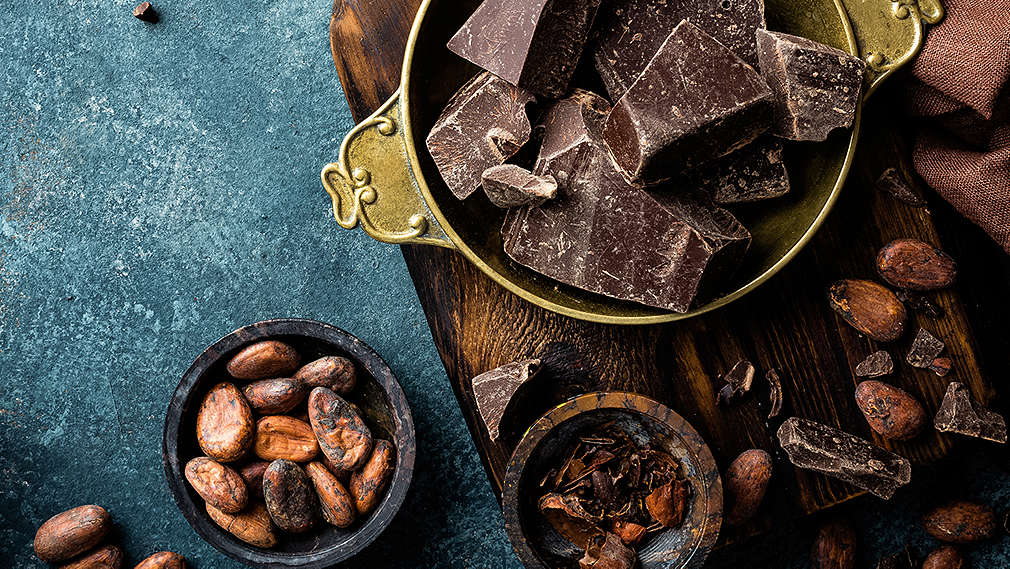 Schokolade und Kakaobohnen, angerichtet in unterschiedlichen Schälchen 