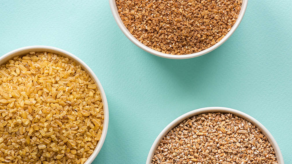 Top-Shot von unterschiedlichem Schrot in drei Schälchen auf türkisfarbenem Hintergrund