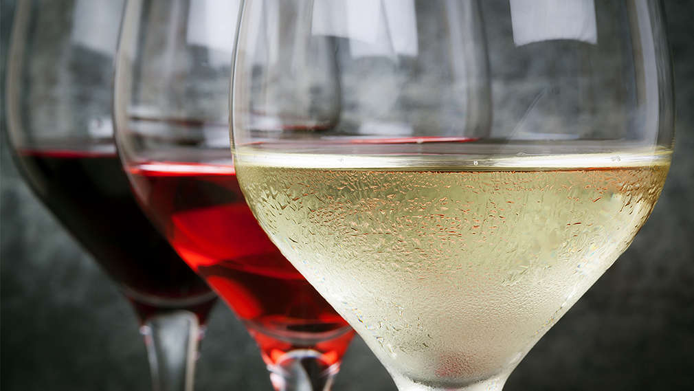 Mehrere Gläser Wein hintereinander gefüllt mit Weißwein, Roséwein und Rotwein