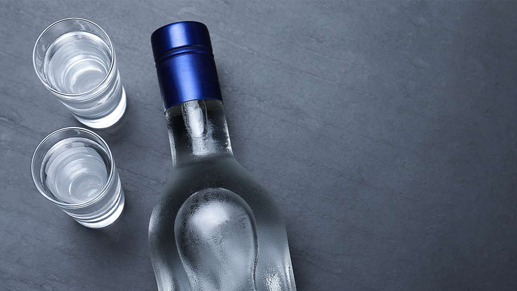 Ein Flasche Wodka im Anschnitt, daneben zwei Schnapsgläser