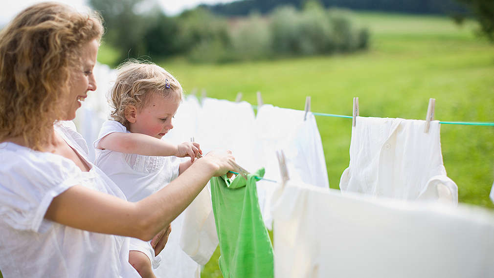 Frau und Kind hängen Wäsche auf Wäscheleine