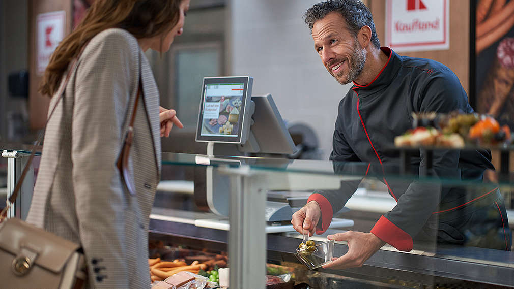 Mitarbeiter an der Frischetheke mit Kundin im Gespräch