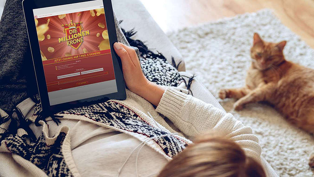 Femeia stă pe canapea și citește newsletter-ul Kaufland