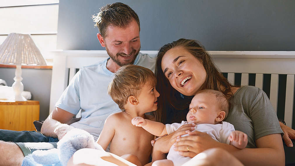 Eltern und Kinder sitzen gemeinsam auf einem Bett