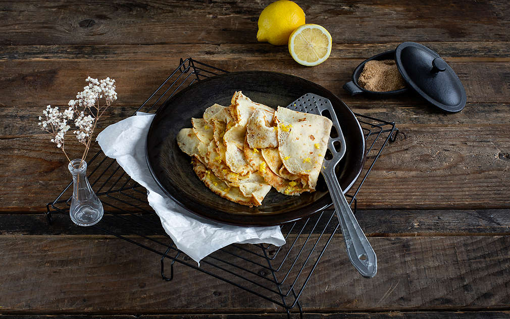 Hrpa tankih palačinki s koricom limuna složenih na tanjuru.
