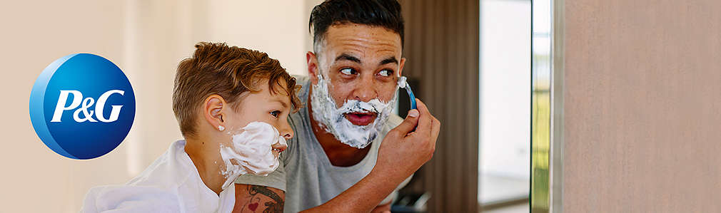 Mann mit Kind im Badezimmer: Mann rasiert sich, Kind hat Rasierschaum im Gesicht