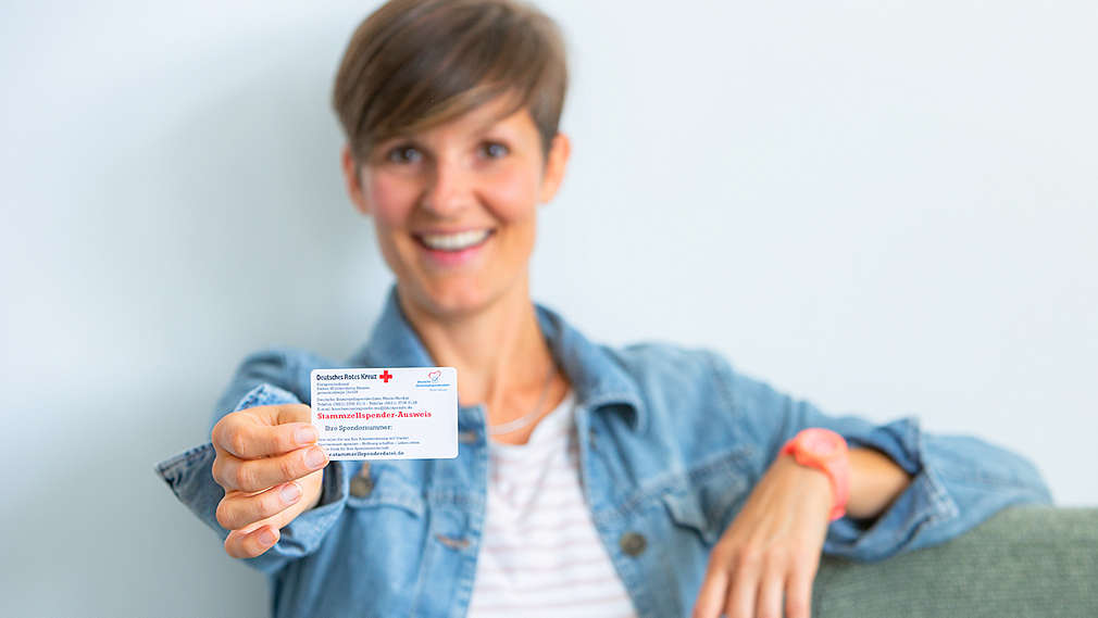 Mitarbeiterin zeigt ihren DKMS Spendenausweis