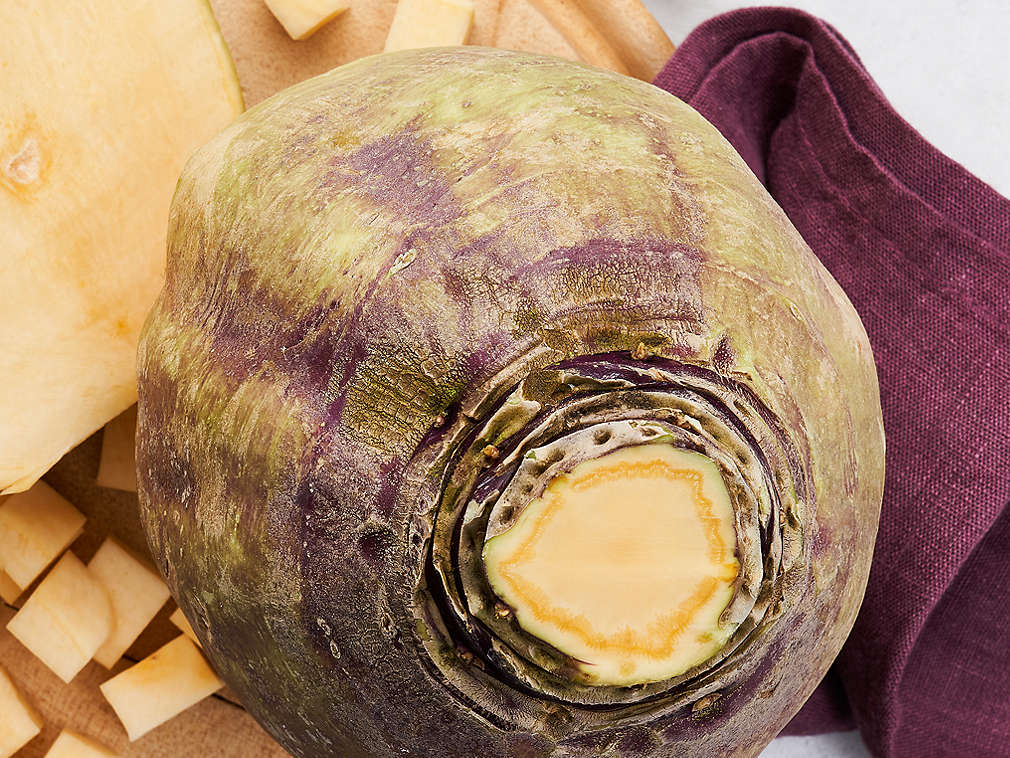 Un nap suedez în detaliu, sub el se află un prosop de bucătărie de culoarea vinului roșu și un tocător din lemn