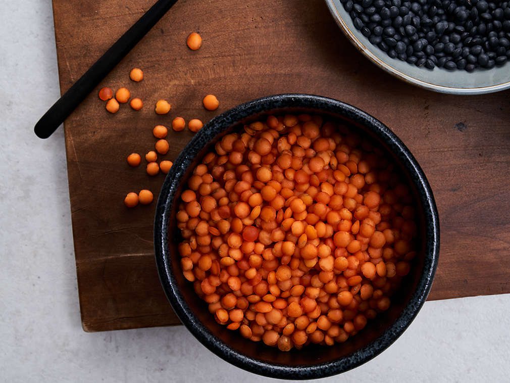 Linte proaspătă într-un bol așezat pe un tocător din lemn