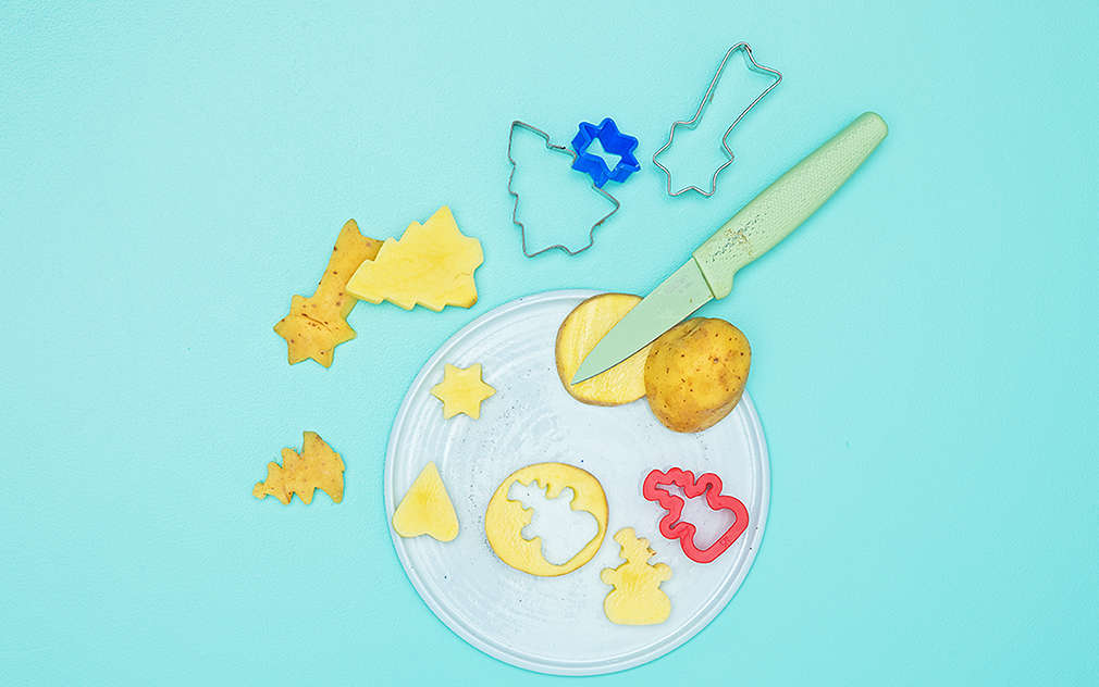 Na talerzu leżą ziemniaki z wyciętymi motywami, kilka foremek do ciastek i nóż.