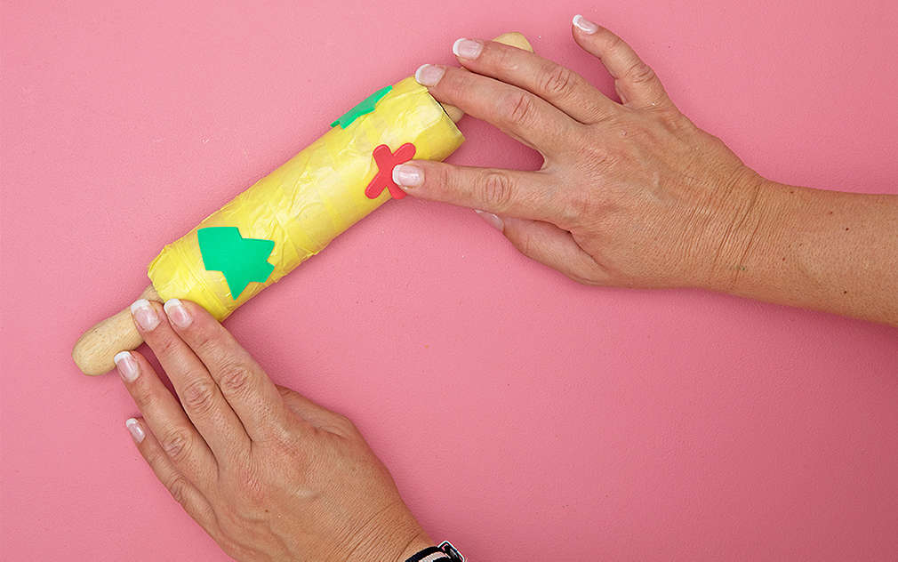 Dwie dłonie trzymają wałek ozdobiony stemplami.